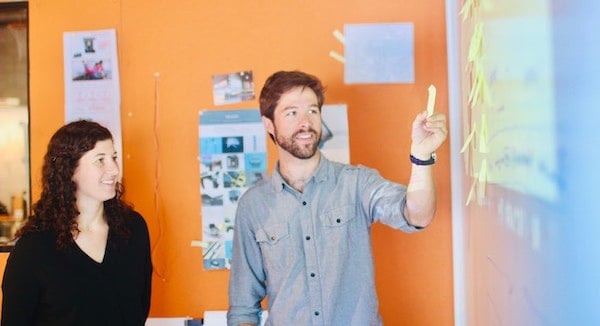 Two team members placing post-its on a whiteboard.