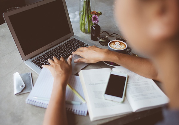 Click the photo of a woman working on a laptop at a crowded desk to get 12 tips for writing business blogs. 